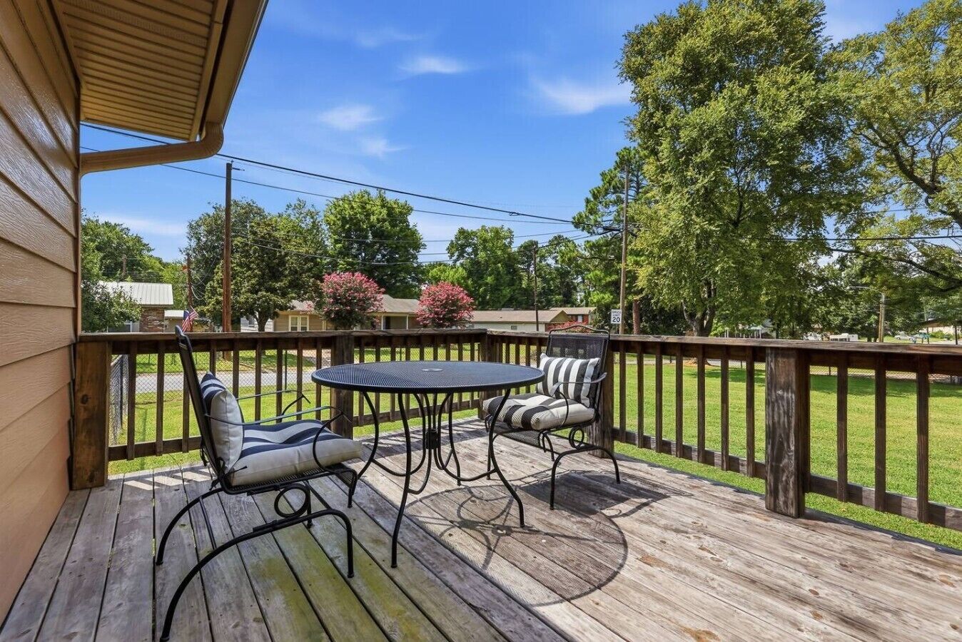 Une terrasse extérieure avec une table et deux chaises, entourée d’une plateforme en bois et d’une rambarde en bois.