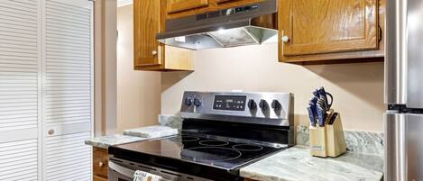 A kitchen with wooden cabinets, a stainless steel stove, and a marble countertop.