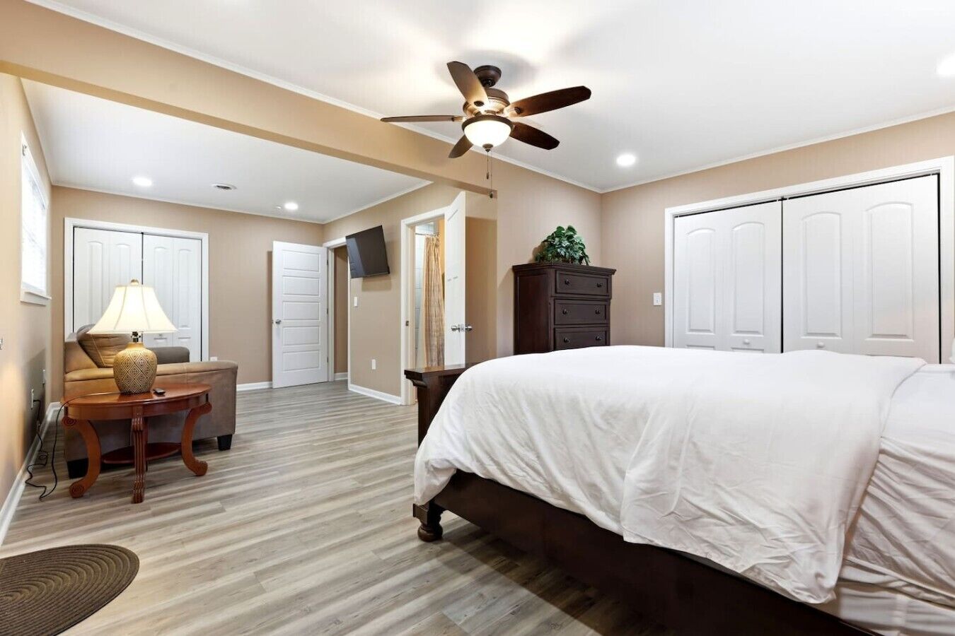 Une chambre à coucher avec un lit, un ventilateur de plafond, un bureau avec une lampe et une commode.