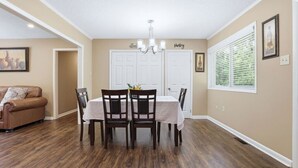 A dining area with a table set for four, a brown leather sofa, and a chandelier. - Peaceful North Little Rock Home w Backyard! (North Little Rock)