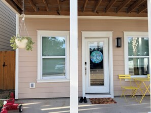 A house with a front porch, a hanging planter, a door with a 'Welcome to our Beach Home' sign, and a yellow folding table. - Happy Zen Retreat - Family's Perfect Beach Retreat (Panama City Beach)