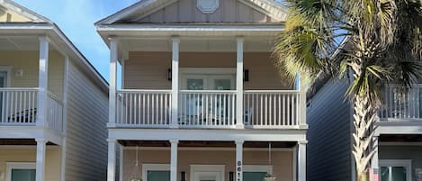 A two-story building with a balcony, a front door, and a small porch area.