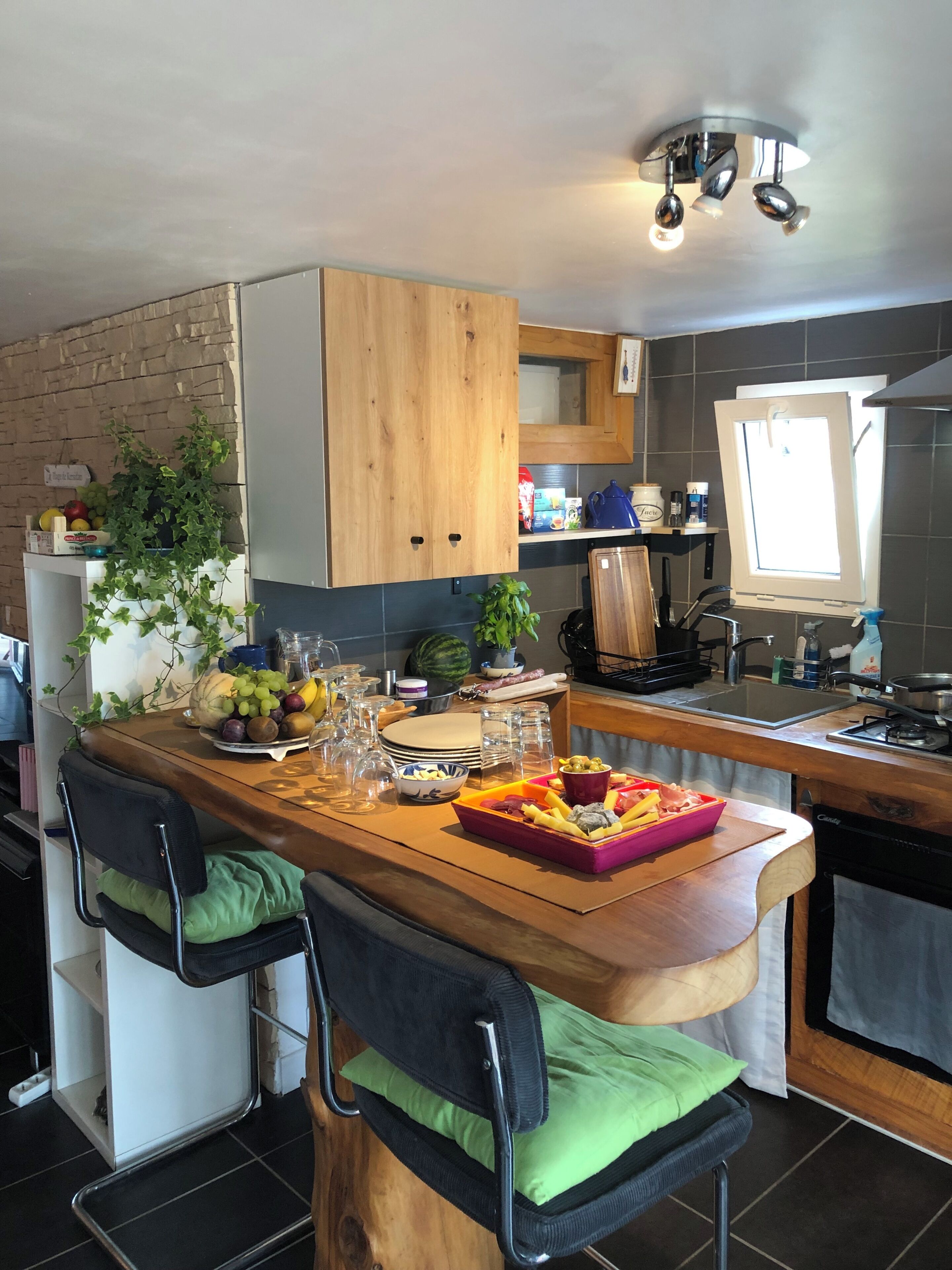Cocina con armarios de madera, una isla integrada con asientos, un ventanal y varios electrodomésticos.