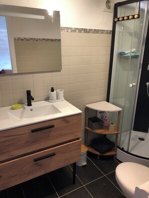 A bathroom with a white sink, wooden vanity, a glass shower enclosure, and a toilet. - Rosel Apartment, 300 meters from Kersidan Beach (Trégunc)