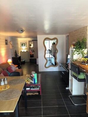 Ein modernes Wohnzimmer mit Essbereich, einer Küche mit Backsteinwand und einem großen Spiegel.