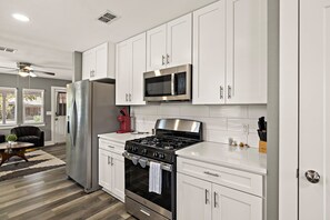 A modern kitchen with stainless steel appliances, white cabinetry, and a black stove. - Charming Bungalow - Walk to Georgetown Square (Georgetown)