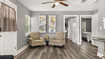 A living room with two armchairs, a ceiling fan, and artwork on the walls.