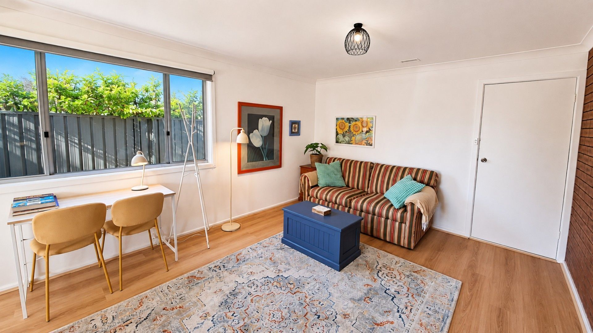 A room with a desk, two chairs, a sofa, a coffee table, and a patterned rug.
