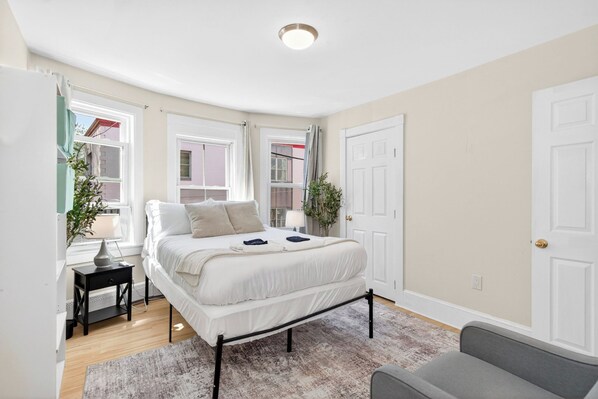 A bedroom with a bed, bedside tables, a rug, and a door.