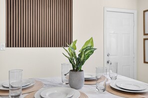 Una mesa de comedor dispuesta con platos, vasos y una planta en maceta.