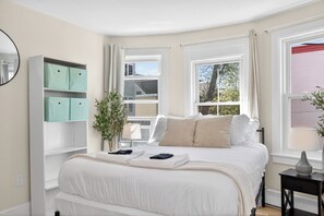 Un dormitorio con cama, ventana, mesita de noche y armario.