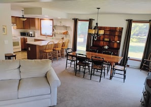 A modern kitchen with a dining area, a sofa, and a view of the outdoors. - Charming house in tranquil North Western Mesick, Michigan for a relaxing getaway (Mesick)