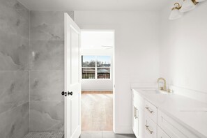 Ein modernes Badezimmer mit Dusche, Waschbecken und Blick ins Freie.
