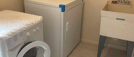 Un cuarto de lavandería con lavadora, secadora y lavabo.