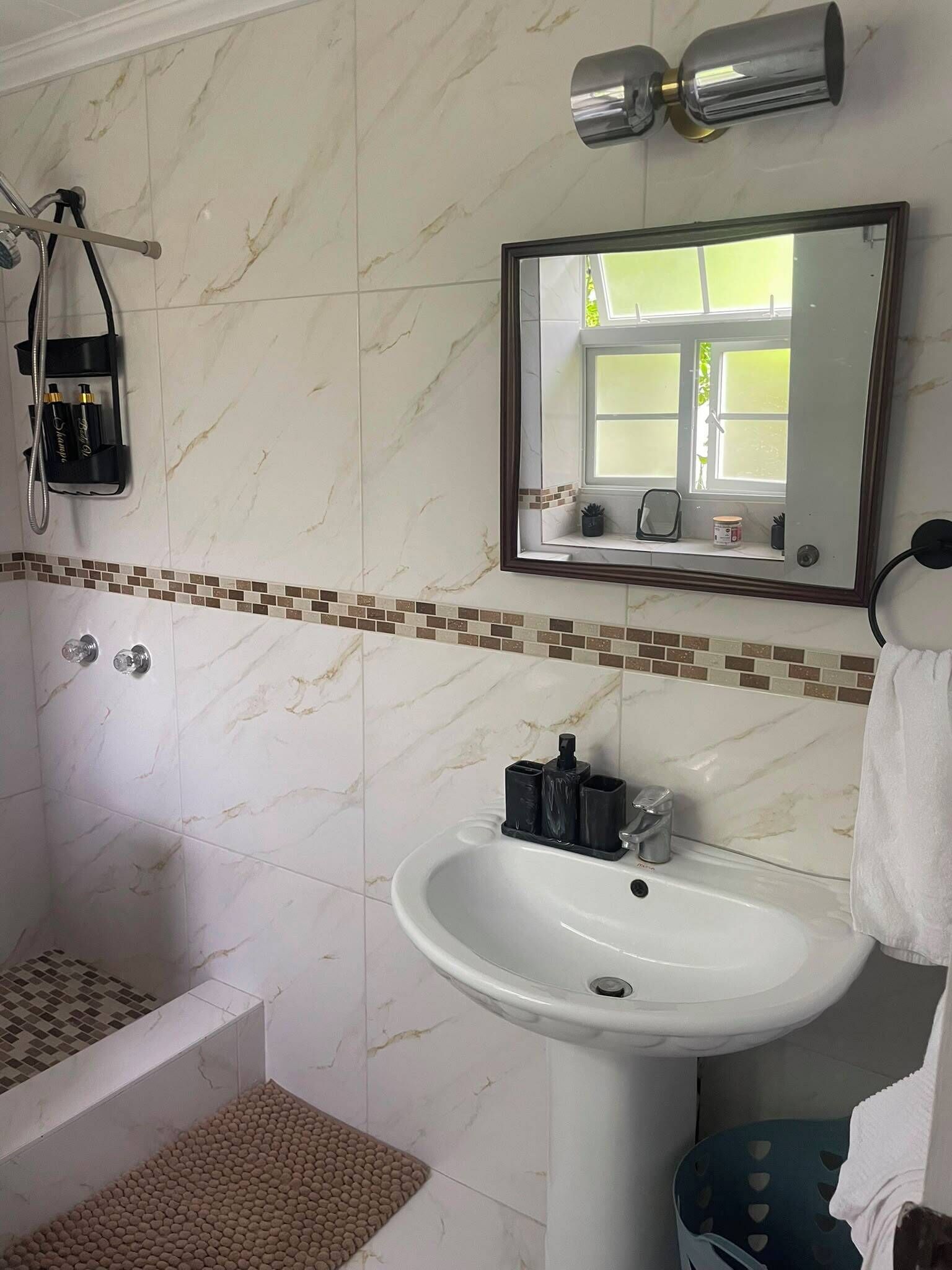 A bathroom with a shower, a sink, and a mirror.