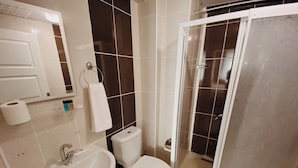 A bathroom with a sink, toilet, and shower area.