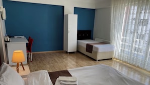 A hotel room with a bed, a desk, a chair, a wardrobe, and a window with curtains.