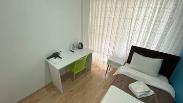 Quarto de hotel com uma cama, uma escrivaninha e uma cadeira.