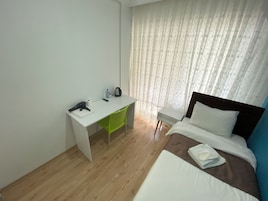 A hotel room with a bed, a desk, and a chair.