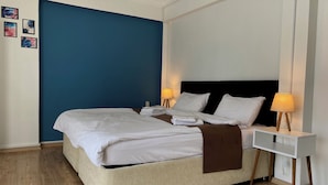 A hotel room with a bed, bedside tables, lamps, and a blue accent wall.