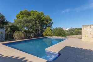 A swimming pool with clear blue water, surrounded by a stone patio and lush greenery. - Holiday Home 'Binitati' with Private Pool, Private Terrace and Private Garden (Sant Lluís)