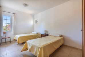 A room with two single beds, a chair, a small table, and a window with curtains. - Holiday Home 'Binitati' with Private Pool, Private Terrace and Private Garden (Sant Lluís)