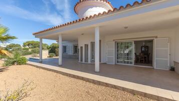 Un área de patio techada con un edificio blanco, columnas y un techo de tejas.