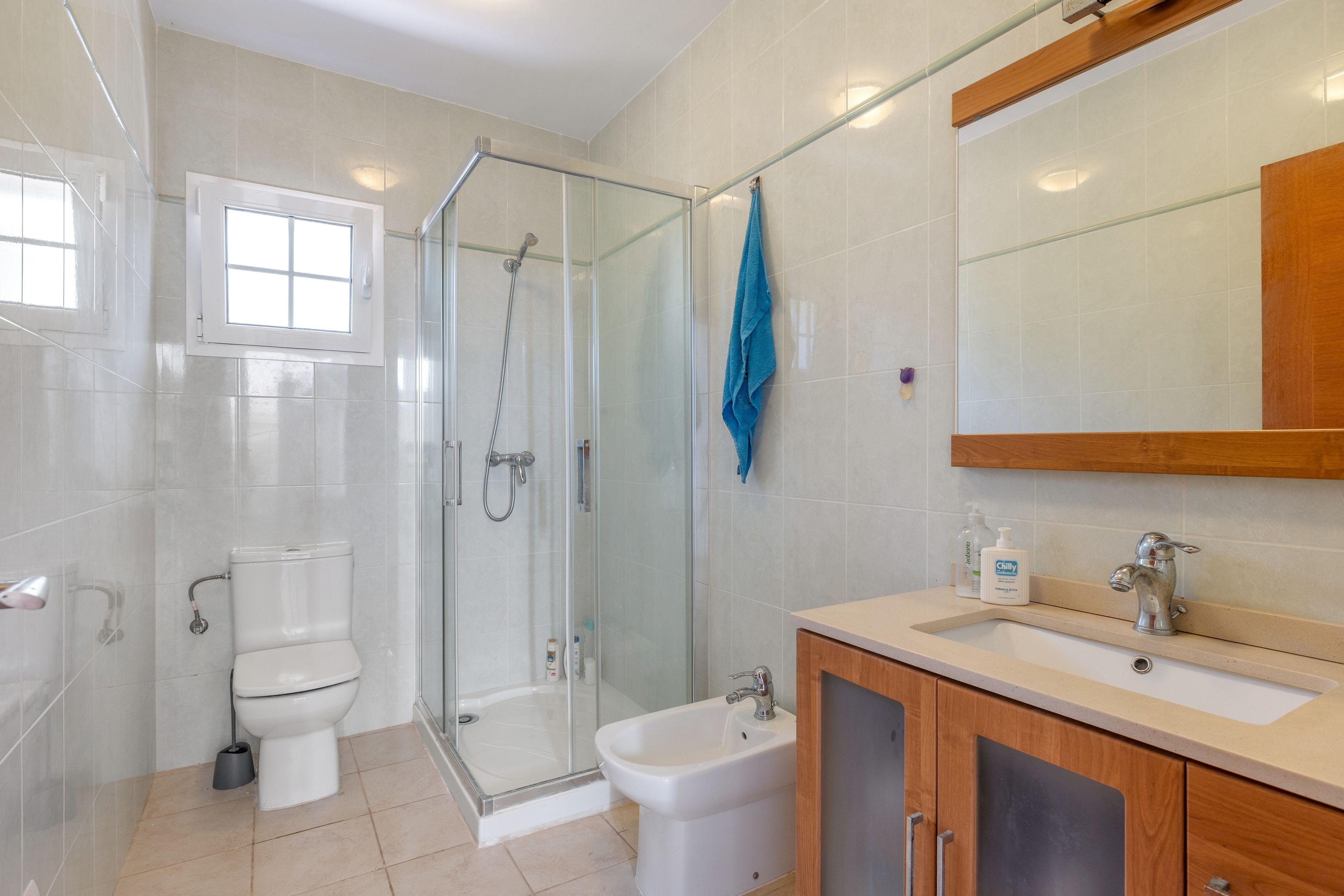 Un baño moderno con cabina de ducha de vidrio, inodoro, lavabo y espejo.