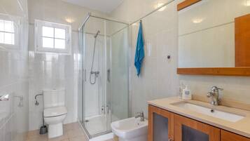 Un baño moderno con cabina de ducha de vidrio, inodoro, lavabo y espejo.