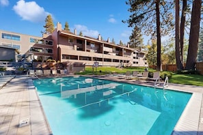 Un hotel con piscina, zona de estar al aire libre y un edificio de varios pisos.