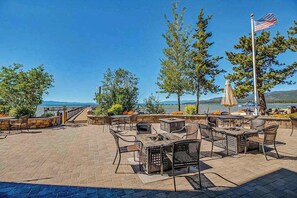 An outdoor patio with tables and chairs, overlooking a body of water and mountains. - Modern Tahoe Retreat - Your Place to Unwind (South Lake Tahoe)