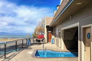 Área de piscina com vista para o mar, um edifício com porta e um pátio cercado.