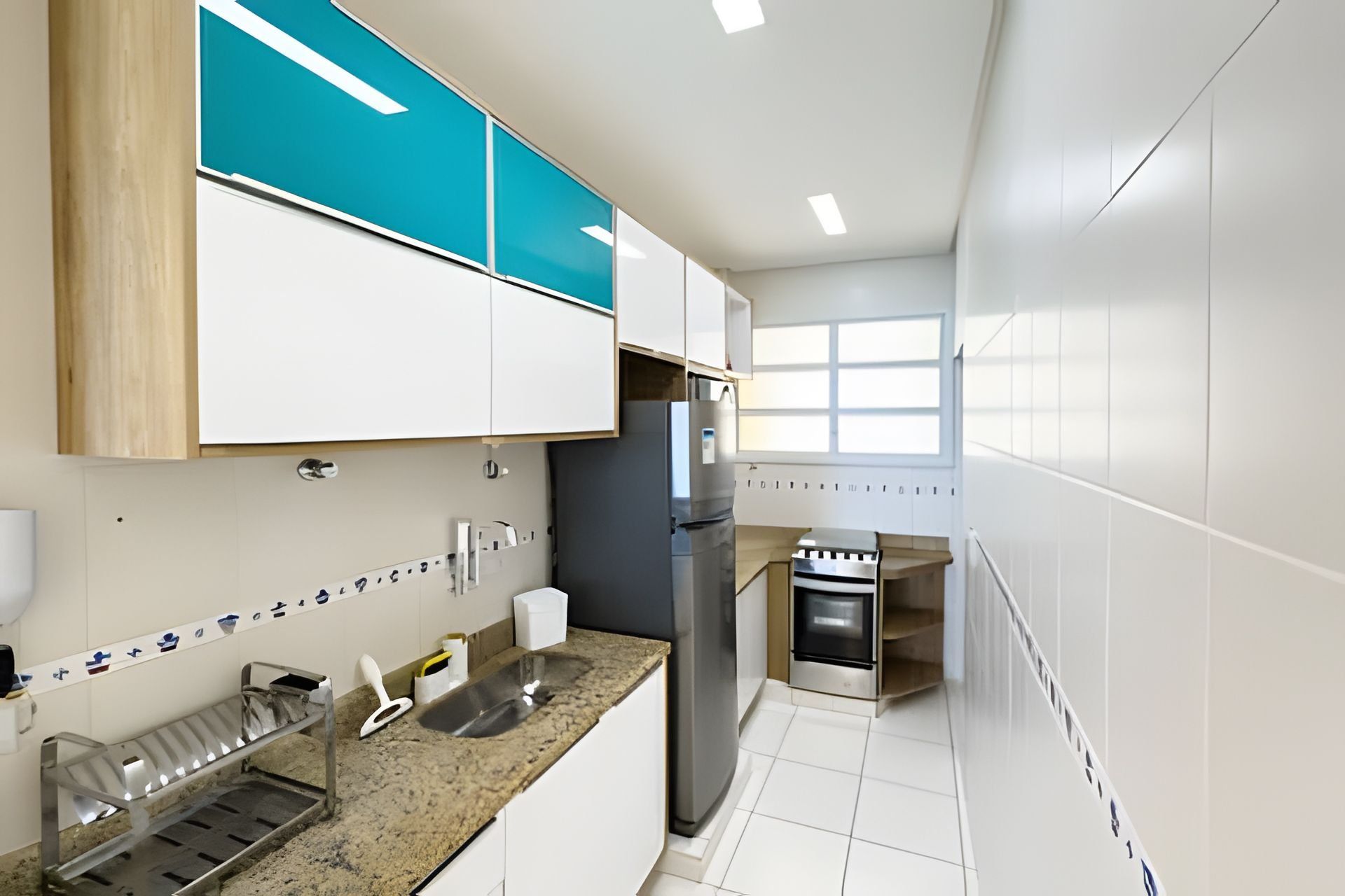 A modern kitchen with white cabinets, a stainless steel refrigerator, and a built-in oven.