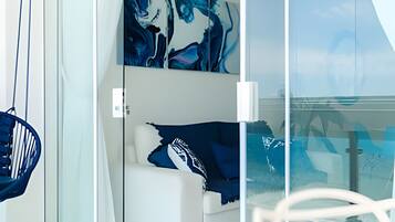 A modern room with a glass partition, a blue chair, and abstract art on the wall.