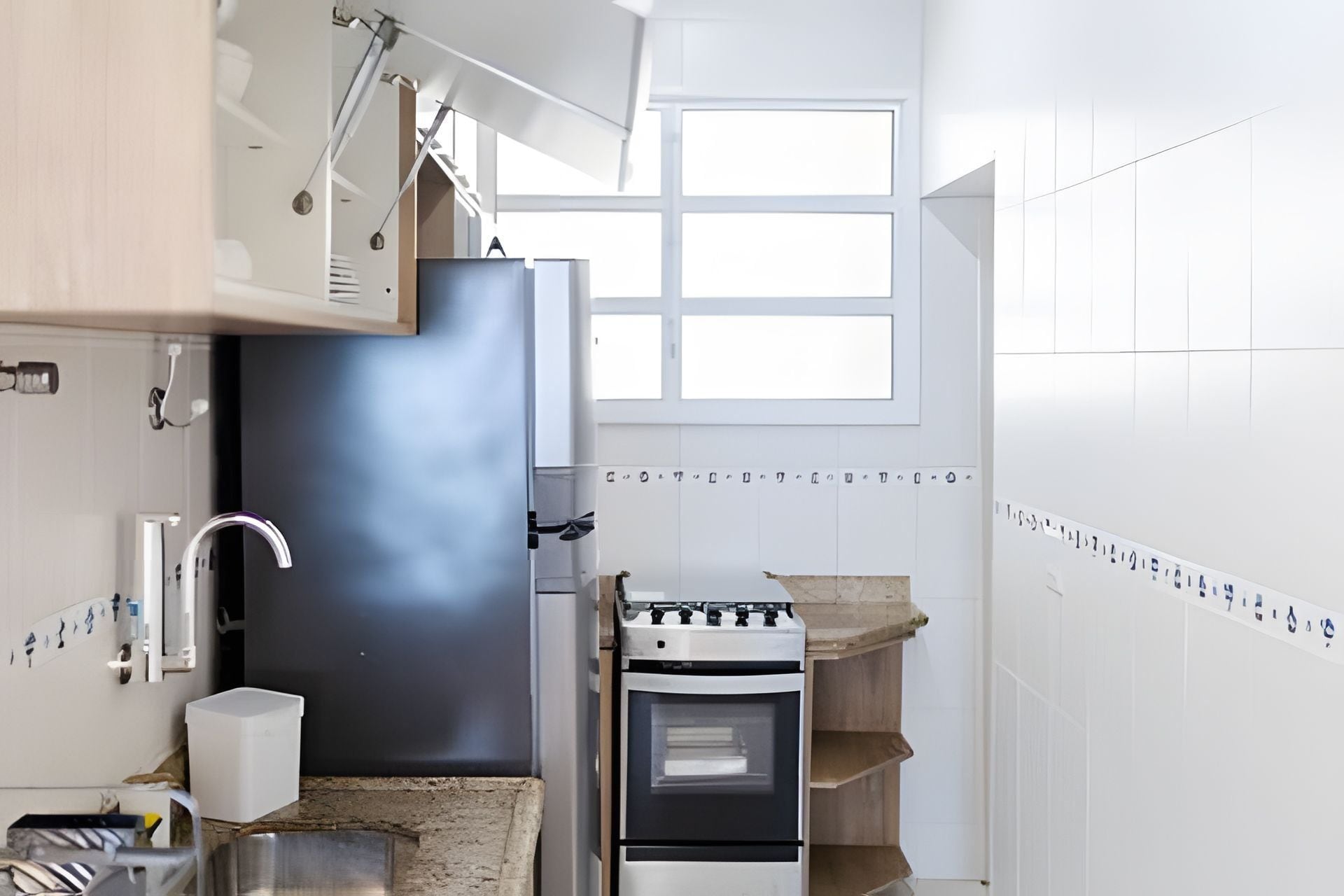A kitchen with a built-in oven, a window, and a tiled backsplash.