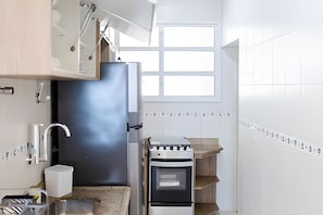A kitchen with a built-in oven, a window, and a tiled backsplash. - SHB - Desperte com o Azul do Mar (Guarujá)