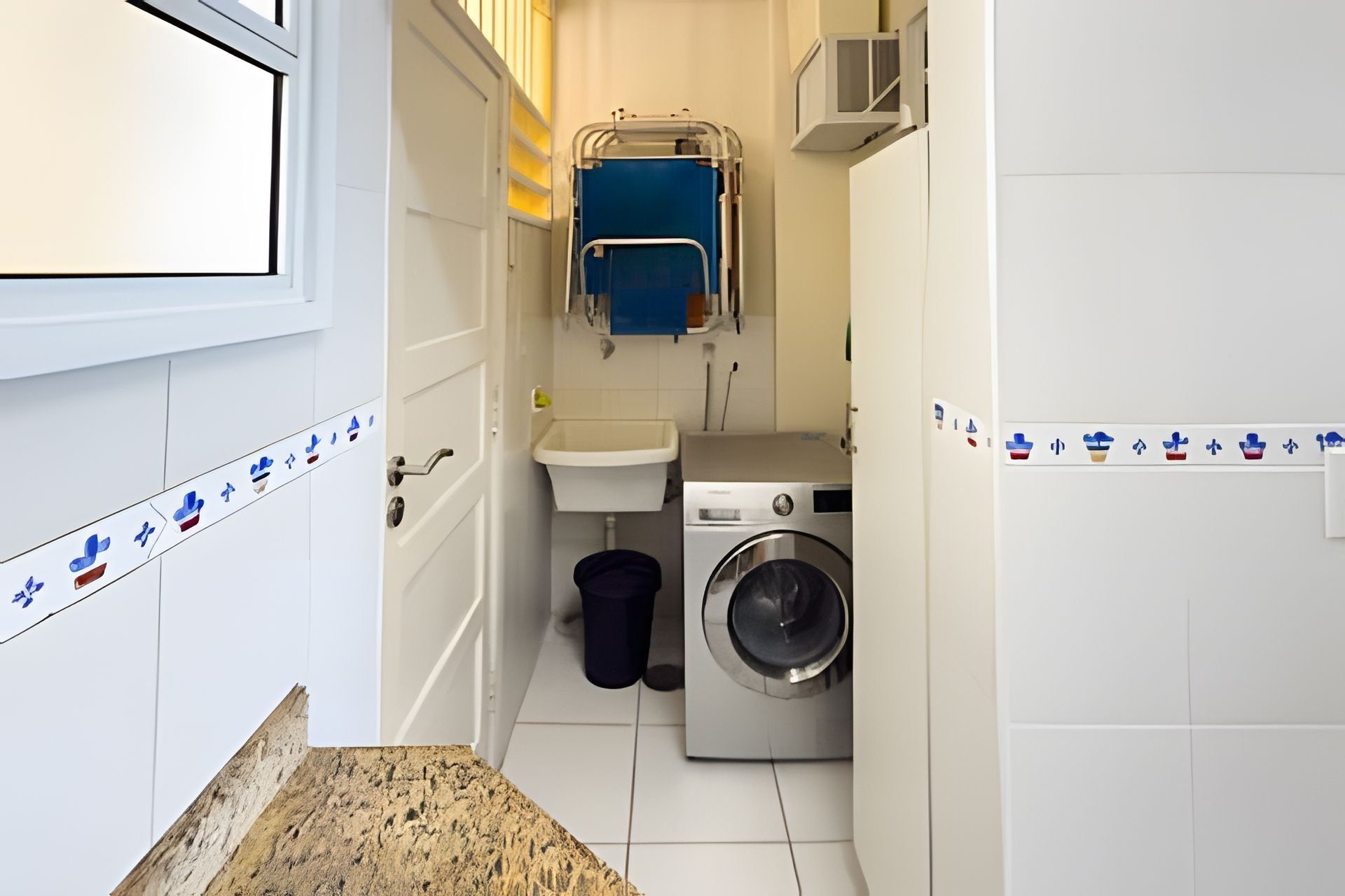 A compact laundry room with a washing machine, a sink, and a towel rack.
