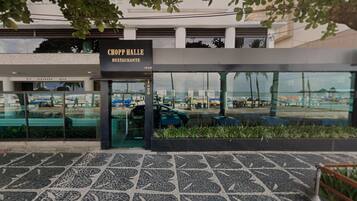 Exterior del restaurante Chop Hall, con un diseño moderno, amplios ventanales de vidrio y una zona de entrada pavimentada.