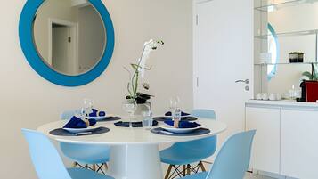 Un comedor con una mesa redonda, sillas azules y un espejo grande en la pared.