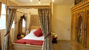 A four-poster bed with floral curtains, a mirror, and a red quilted pillow. - The Potions Room - A Magical Hot Tub Hideaway (Alnwick)