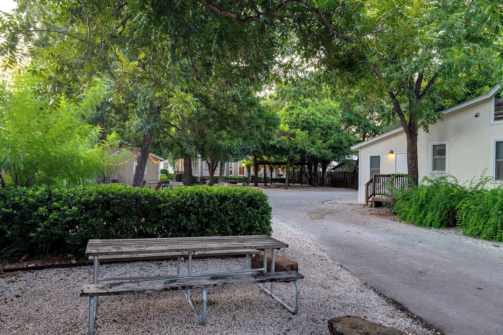 A gravel path leading to a row of cabins with a wooden bench in the foreground.