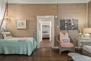 A bedroom with a bed, a chair, a nightstand, a wall clock, and a door leading to another room. - Telegraph Station #2,  Downtown, Pet friendly! (New Braunfels)