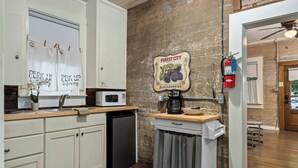 Una cocina con gabinetes blancos, microondas, cafetera y un cartel de moras Forest City.
