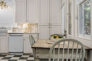 A kitchen with white cabinets, a wooden table, and a window. - Historic Ludwig Haus, Downtown, Pet Friendly! (New Braunfels)