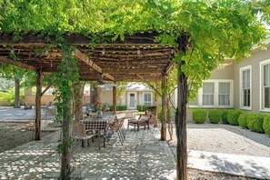 An outdoor patio with a pergola, table, chairs, and a view of a house. - Ludwig Haus, Downtown, Pet Friendly, Fire pit! (New Braunfels)