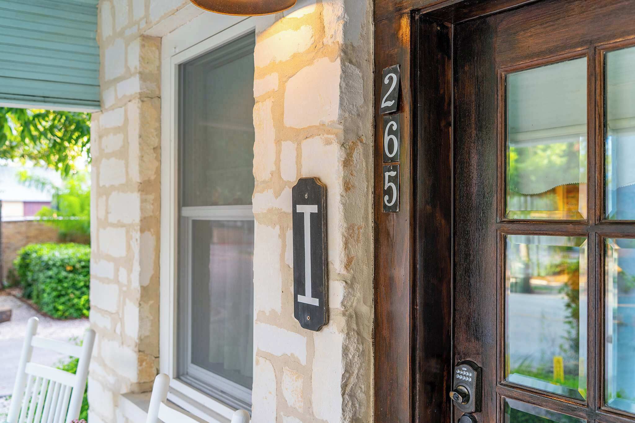 A house number 2655 on a stone wall, a window, and a door with a glass panel.