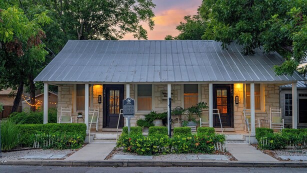 A two-story building with a porch, stone walls, and a signboard. - Telegraph Station #1, Downtown, Pet friendly! (New Braunfels)