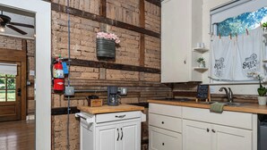 A kitchen with white cabinets, a coffee machine, a fire extinguisher, and a chalkboard menu. - Telegraph Station #1, Downtown, Pet friendly! (New Braunfels)