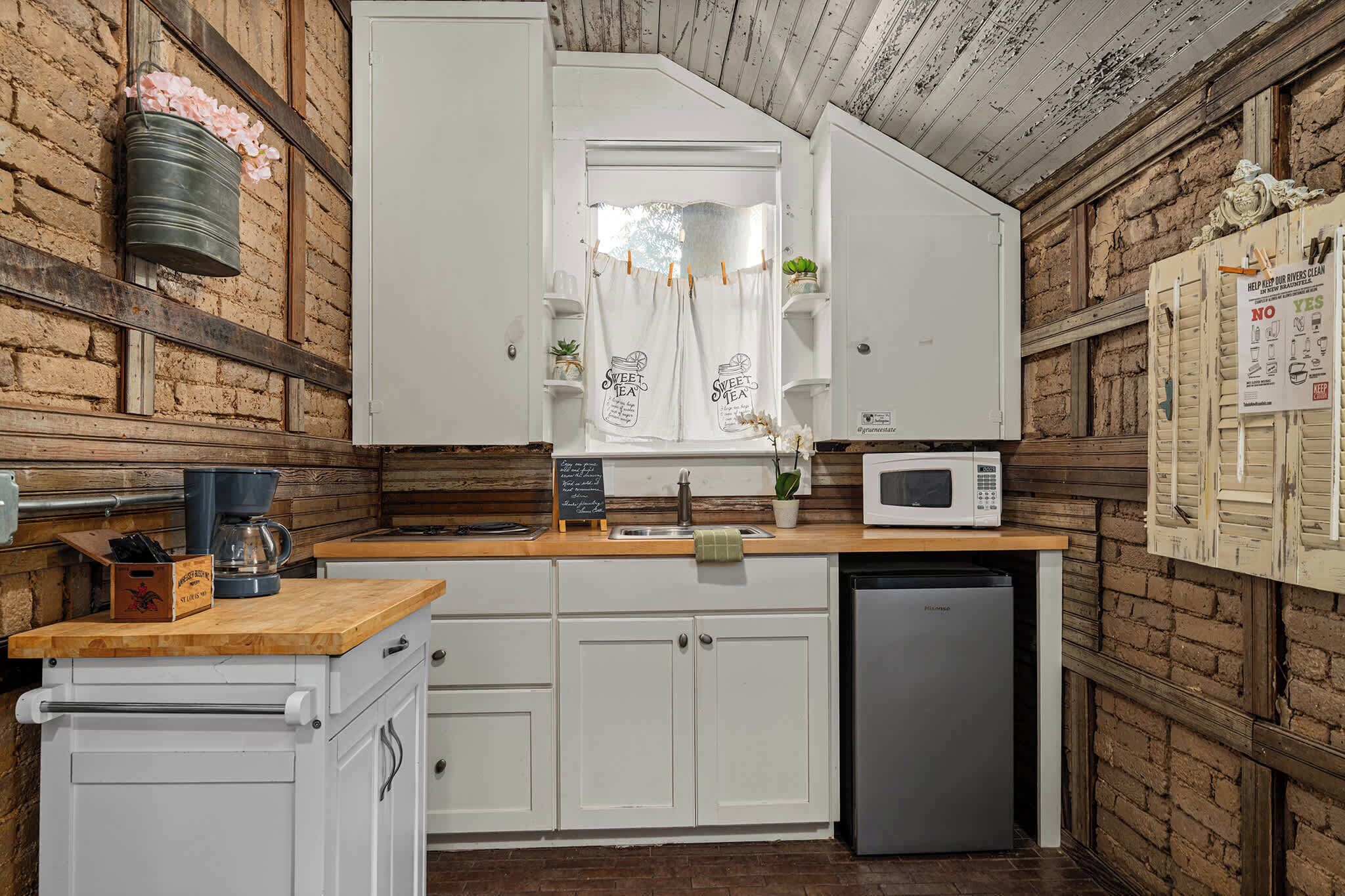 A kitchen with white cabinets, a microwave, a sink, and a wooden countertop.
