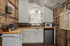 A kitchen with white cabinets, a microwave, a sink, and a wooden countertop. - Telegraph Station #1, Downtown, Pet friendly! (New Braunfels)